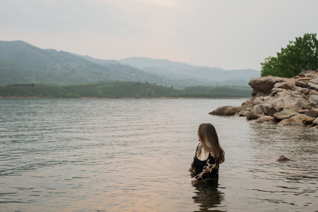 Woman looks at the sunset at a reservoir. Hire a professional book editor with Sirène Storyhouse.